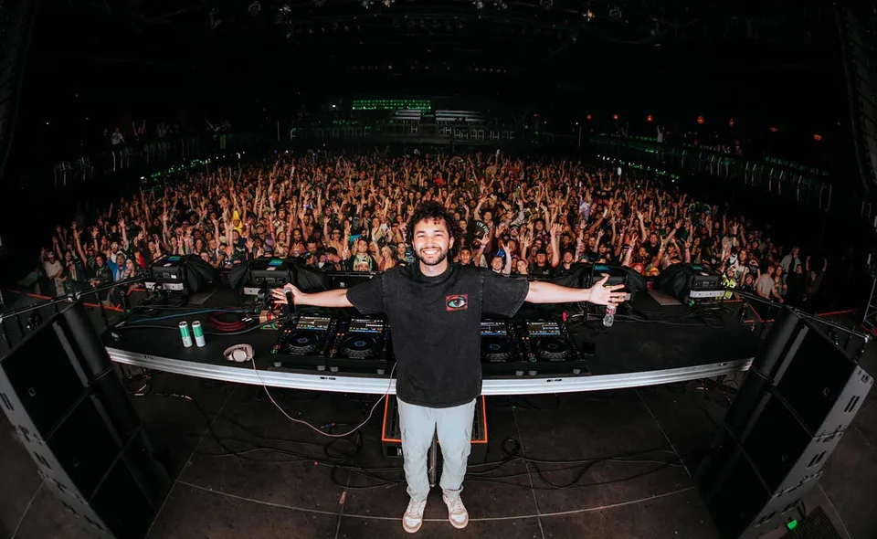 CAPOCHINO standing with arms outstretched in front of a concert crowd.