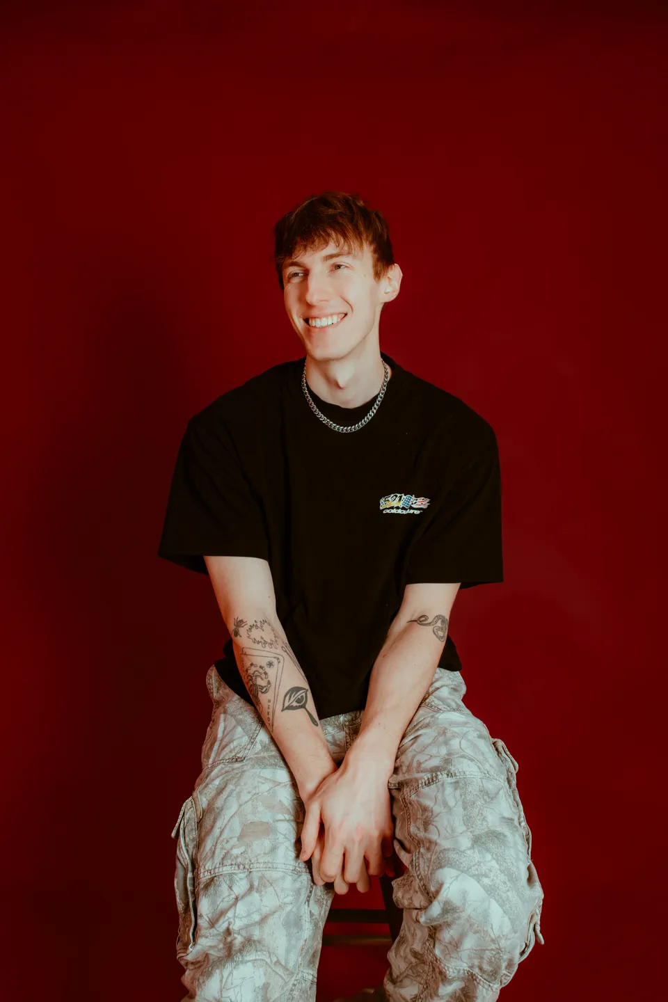 Cyclops smiling while seated against a red studio background.