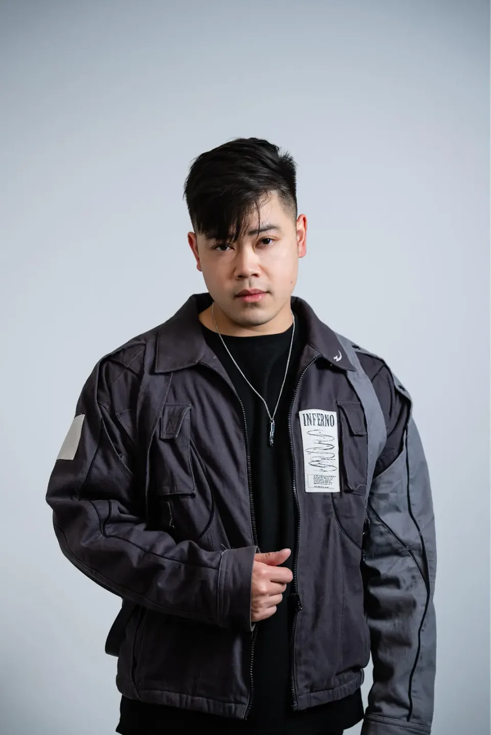 Hoang wearing a dark jacket against a pale grey studio background.