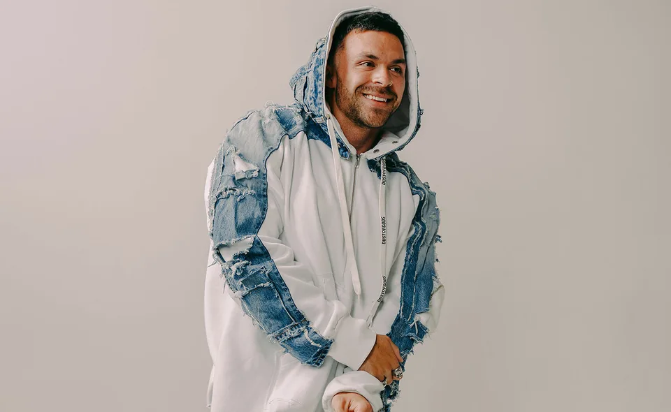 Kai Wachi in a pale hooded jacket against a neutral studio background.