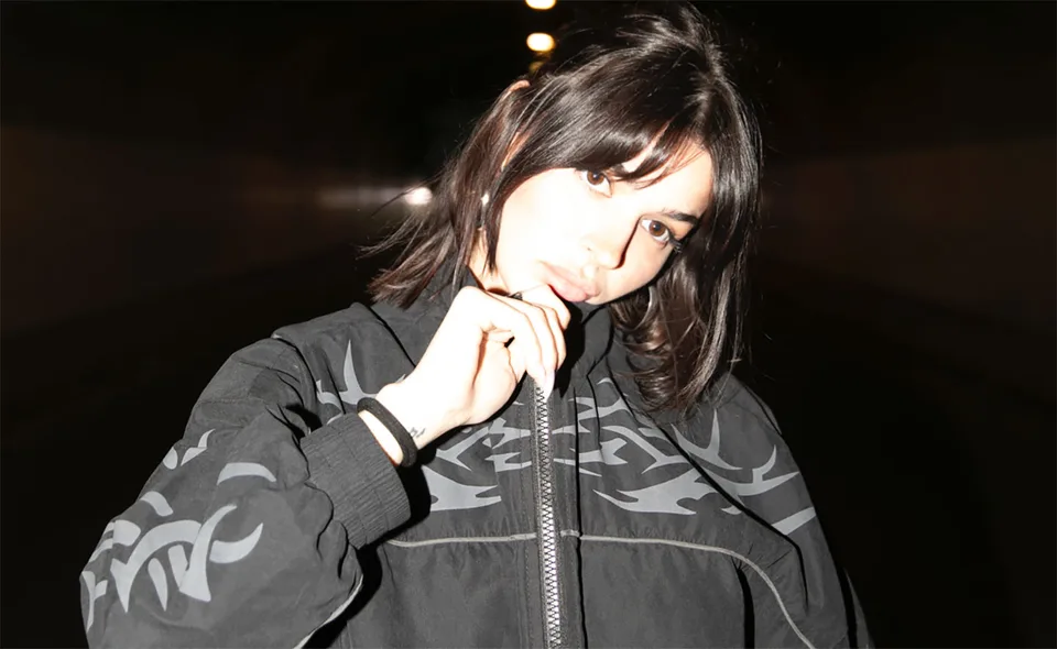 Klo in a patterned jacket, illuminated against a dark background.