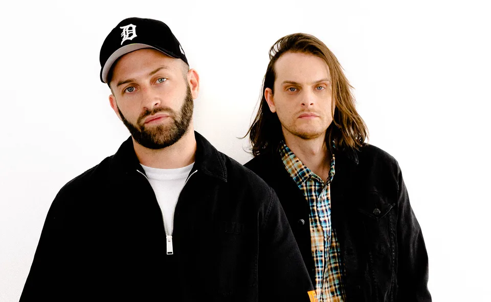 Zeds Dead’s two members in dark jackets against a white studio background.