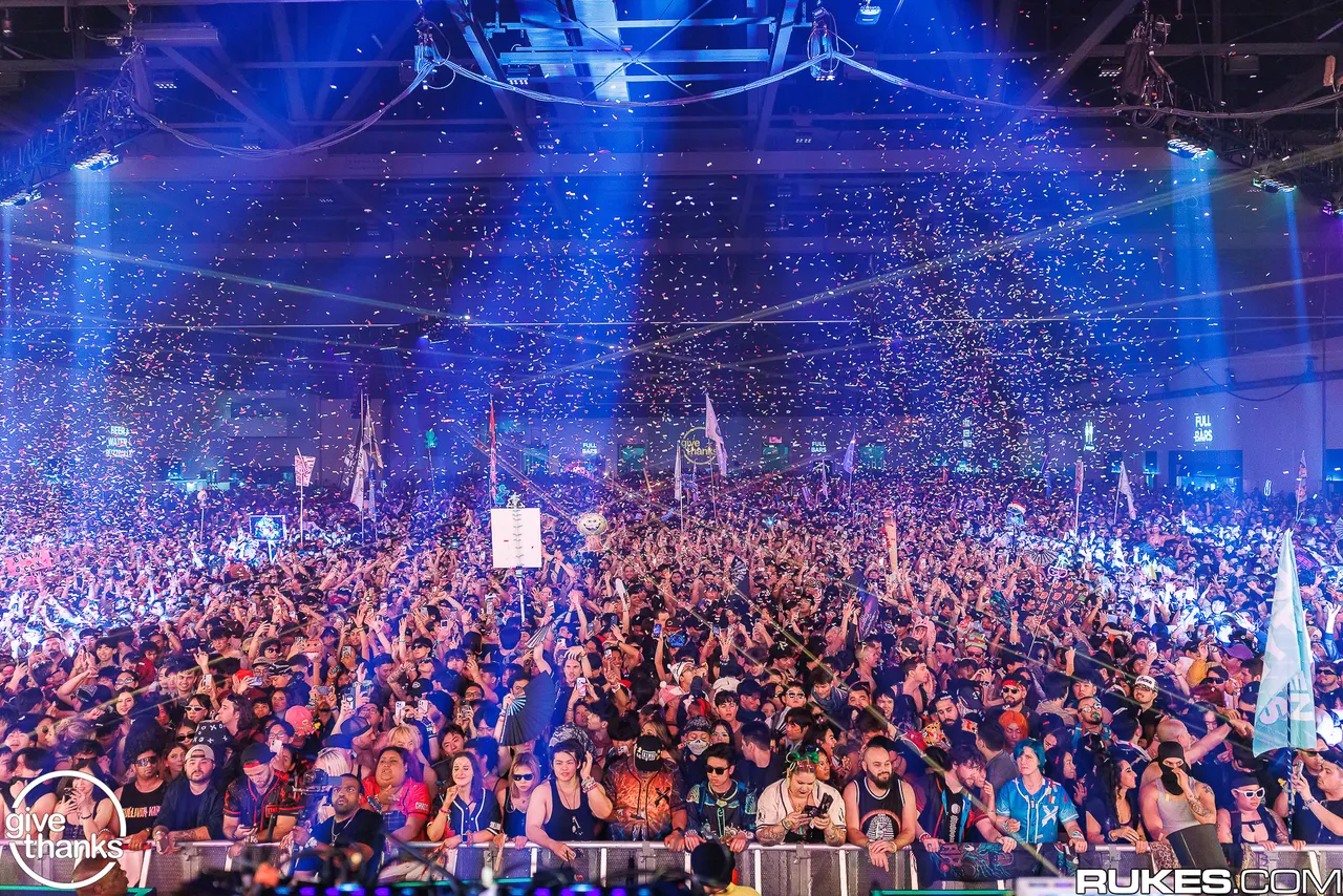 The Give Thanks crowd celebrating beneath blue lights and falling confetti. Photo by Rukes.